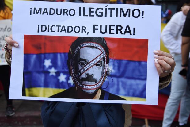 Un cartel con la leyenda "¡Maduro, dictador ilegítimo, fuera!" se alza durante una protesta de venezolanos frente a su embajada en Ciudad de Guatemala, el 23 de enero de 2019. (Foto de Orlando ESTRADA / AFP).